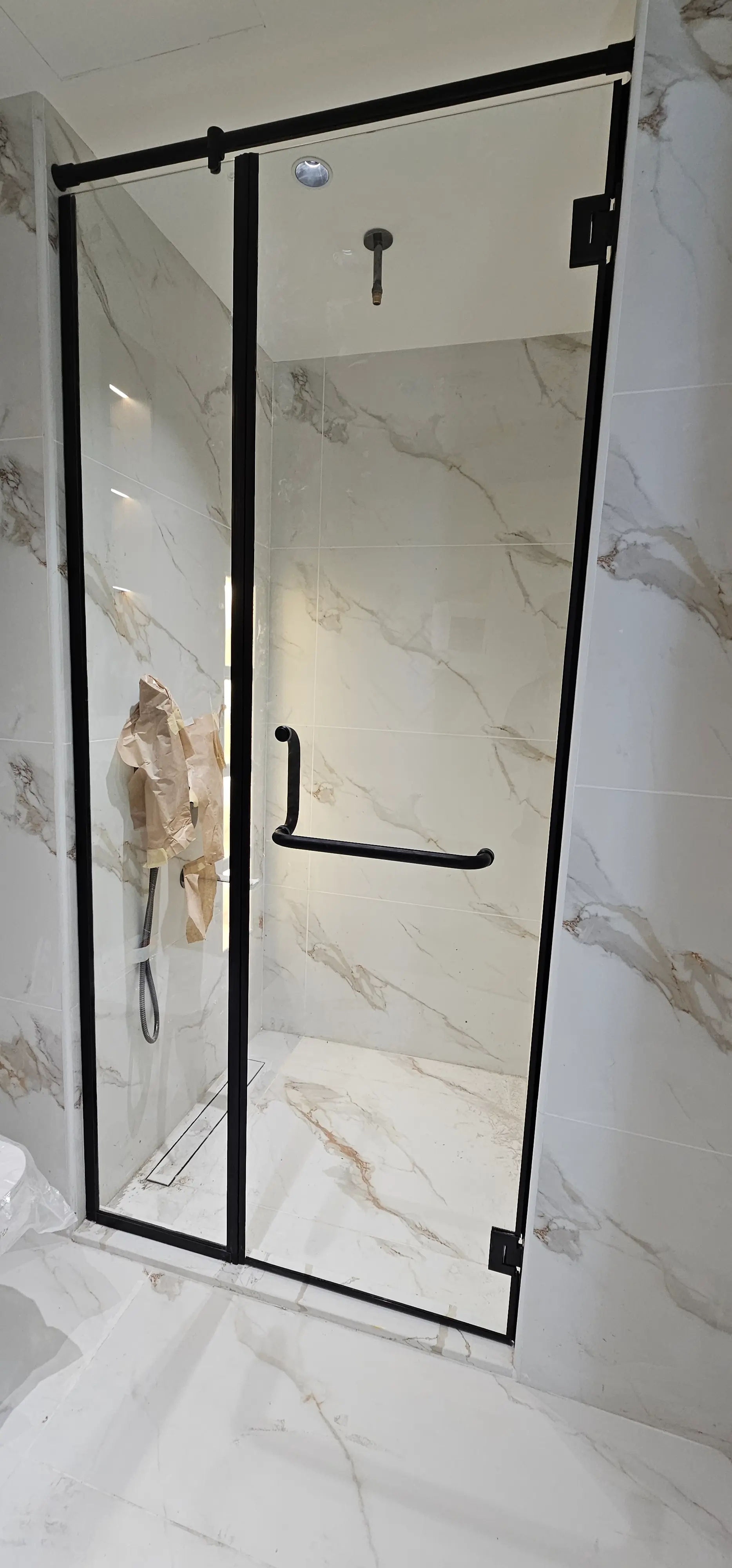 Black-framed glass shower screen with marble tiling installed by Diamond Step UAE