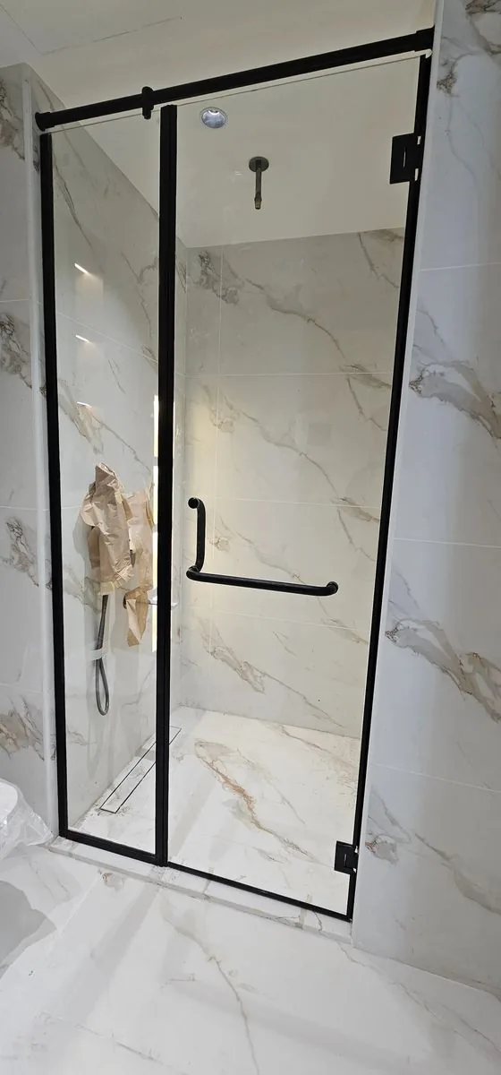 Black-framed glass shower screen with marble tiling installed by Diamond Step UAE