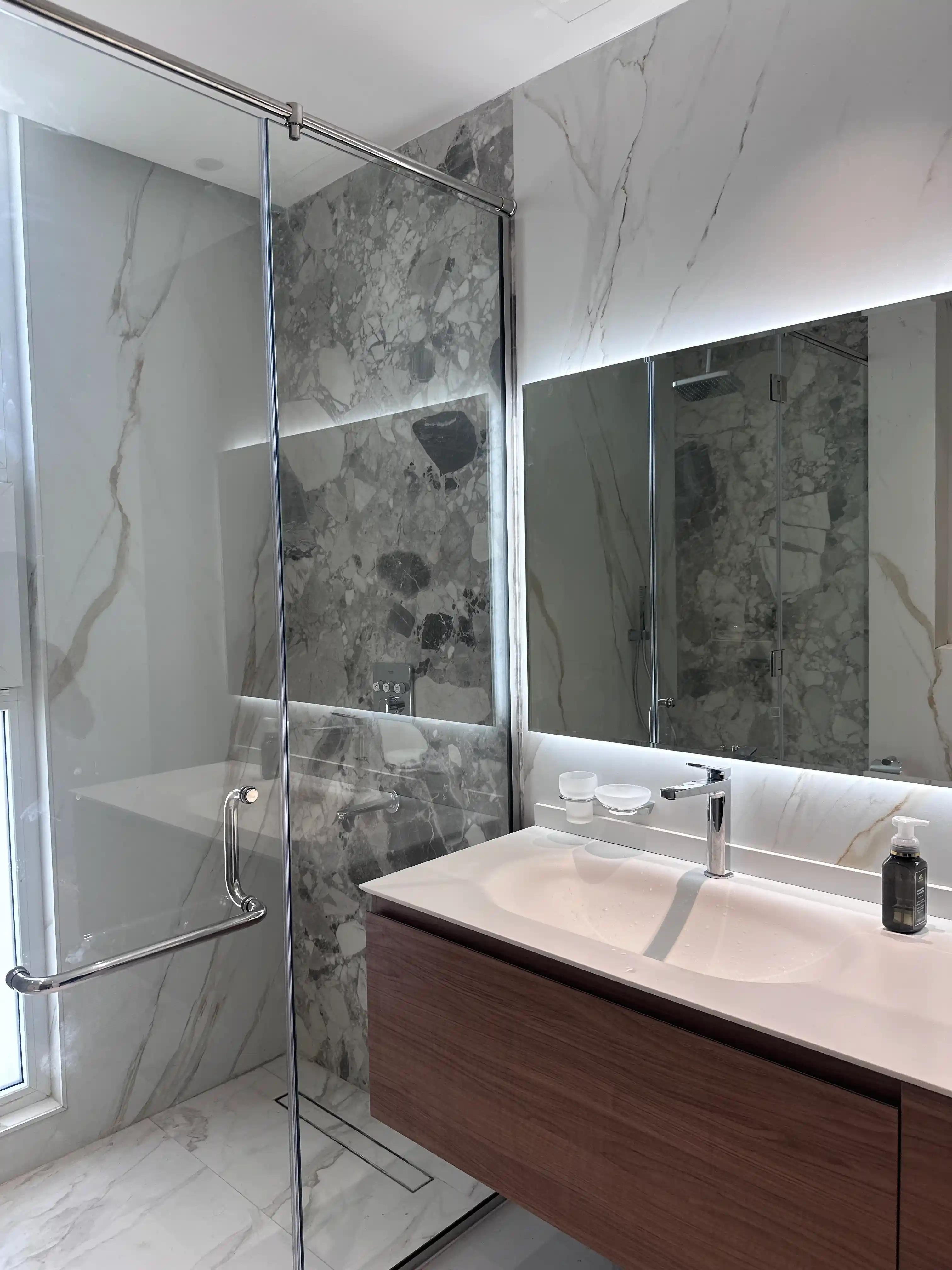 Frameless glass shower enclosure with chrome hardware installed by Diamond Step UAE