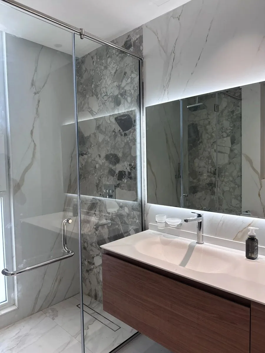 Frameless glass shower enclosure with chrome hardware installed by Diamond Step UAE