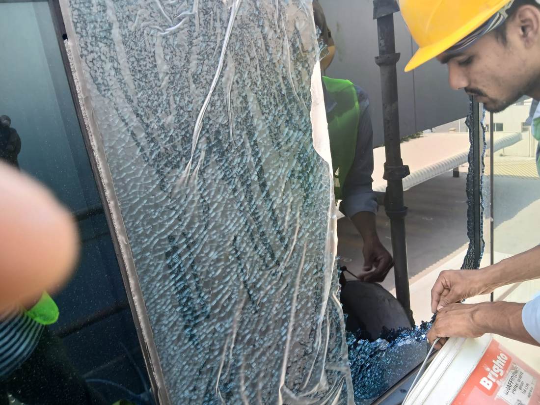 Diamond Step technician safely removing a shattered toughened glass panel from a UAE building facade